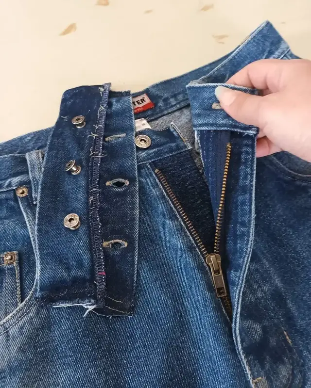 Ceinture d'un jean, ouverte et décousue sur la table de l'atelier