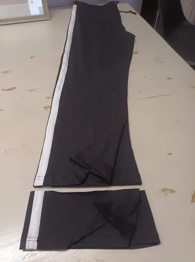 Pantalon noir à bande blanche, le bas des jambes coupé posé dessous
