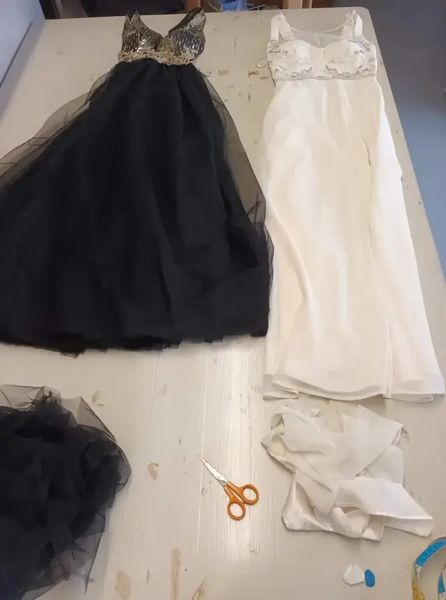 Une robe longue noire en tulle et une robe longue blanche, les chutes de tissu posées dessous