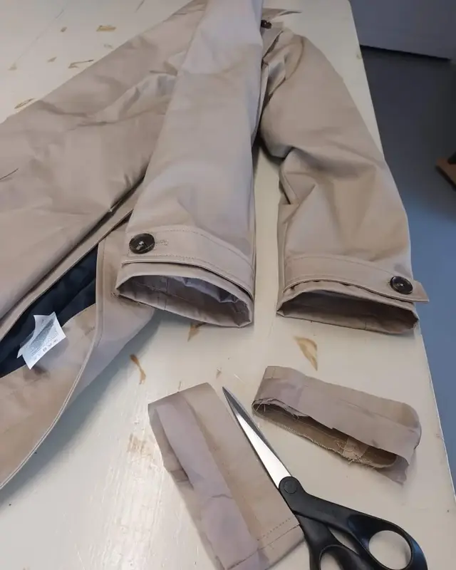 Veste beige, le bas des manches coupé, une paire de ciseaux