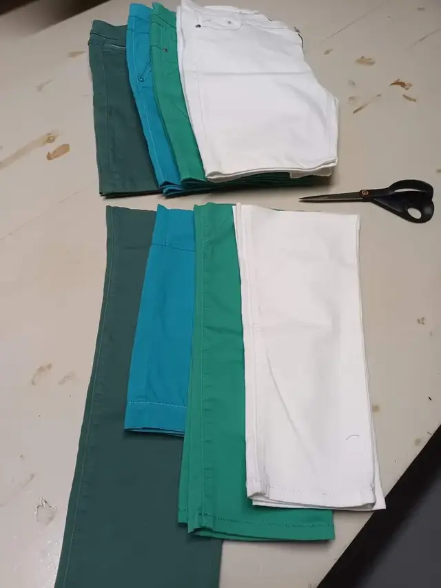 Quatre pantalons, vert, bleu, émeraude et blanc, et une paire de ciseaux